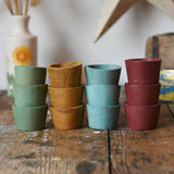 Papoose Toys wooden bowls in earth colours stacked up on a wooden desk.