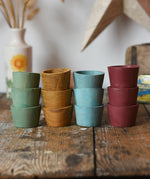 Papoose Toys wooden bowls in earth colours stacked up on a wooden desk.