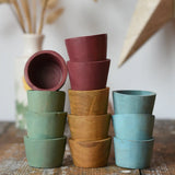 Papoose Toys wooden bowls in earth colours stacked up on a wooden desk.