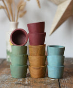 Papoose Toys wooden bowls in earth colours stacked up on a wooden desk.