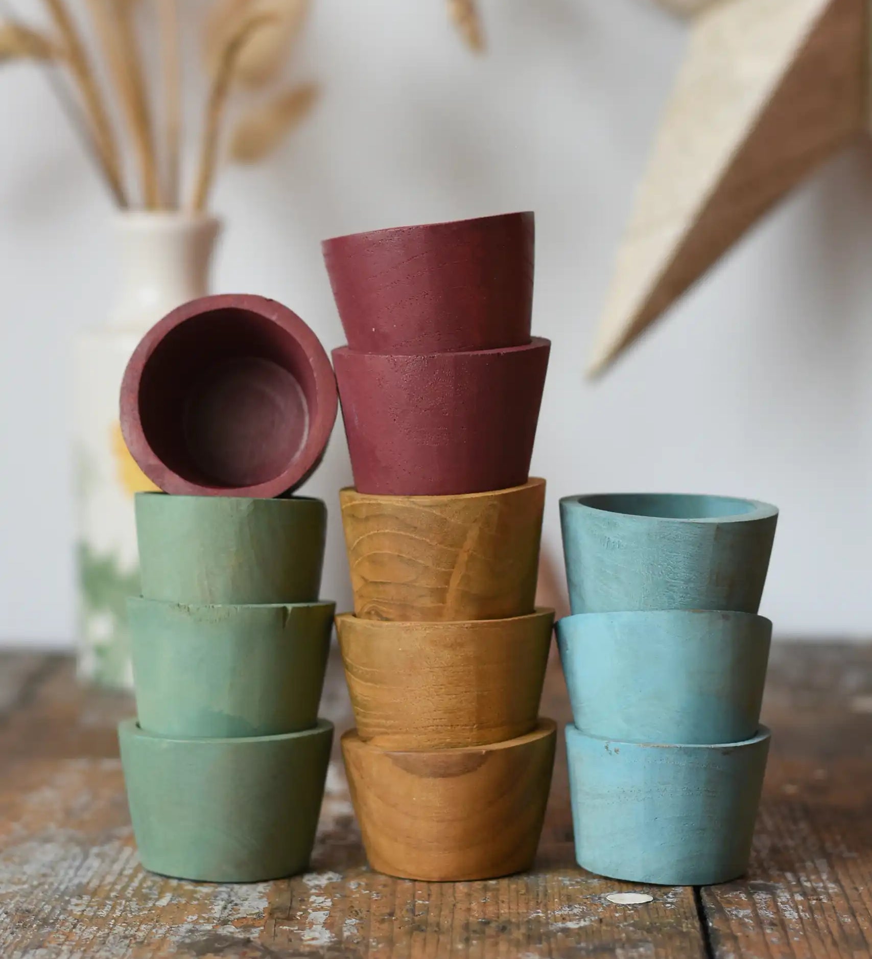Papoose Toys wooden bowls in earth colours stacked up on a wooden desk.