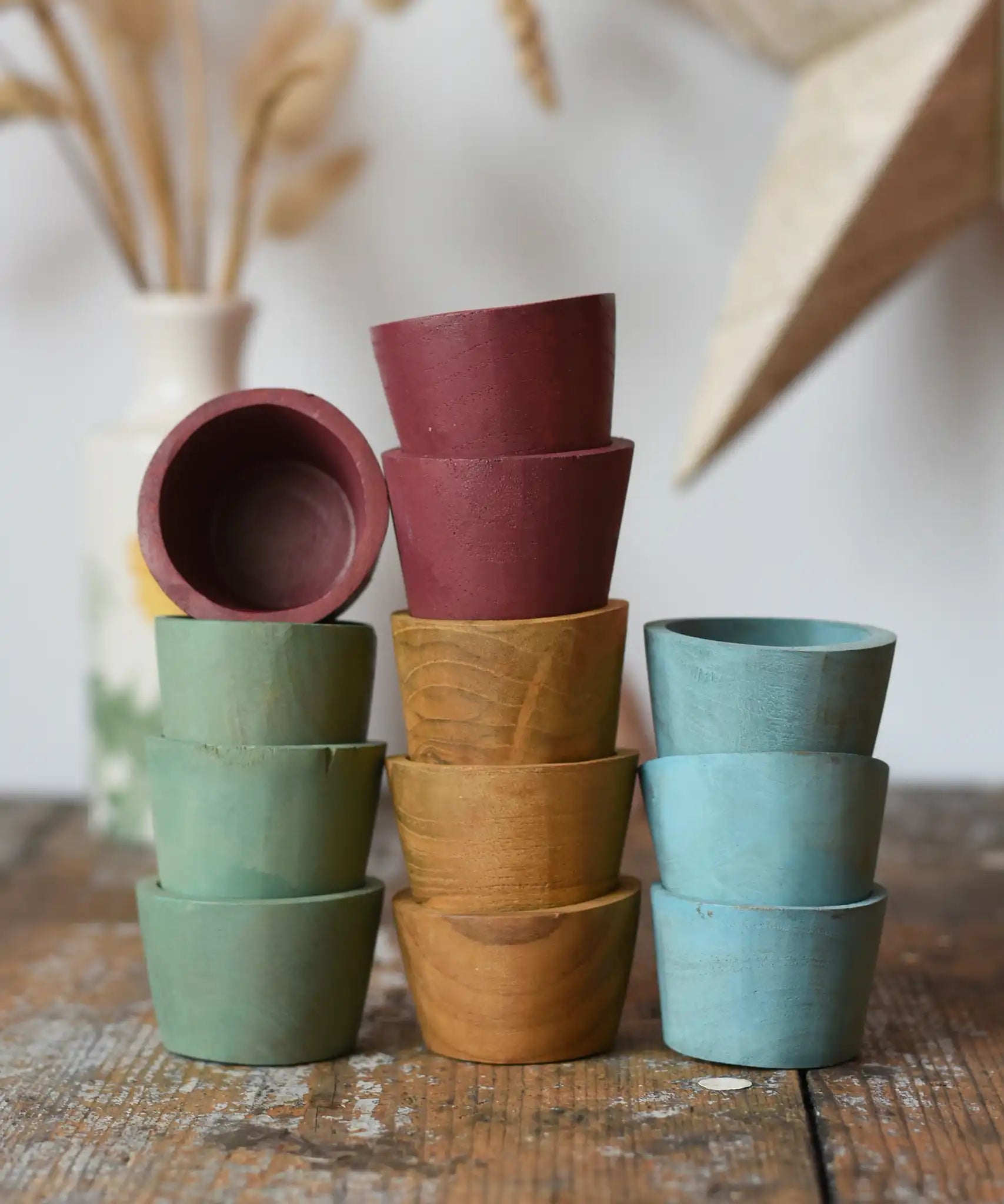 Papoose Toys wooden bowls in earth colours stacked up on a wooden desk.
