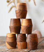 Papoose Toys 12 small natural wooden bowls placed on a wooden desk. 