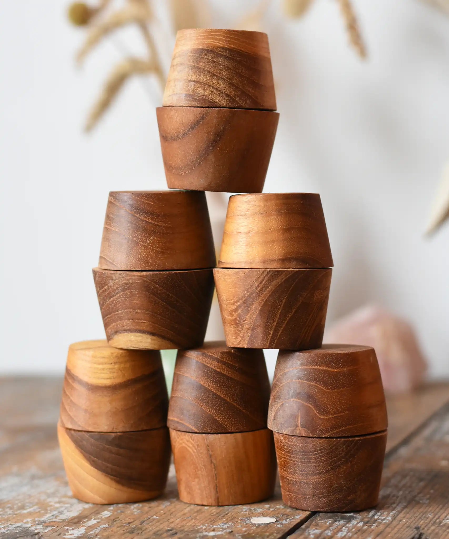 Papoose Toys 12 small natural wooden bowls placed on a wooden desk. 