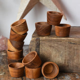 Papoose Toys 12 small natural wooden bowls placed on a wooden desk. 