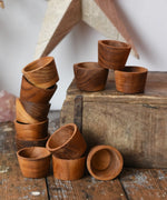 Papoose Toys 12 small natural wooden bowls placed on a wooden desk. 