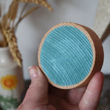 Blue Papoose Toys wooden earth coin in an adult's hand.