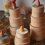 Papoose Toys wooden earth coins stacked up to create cakes with Grapat loose parts on top as candles.