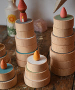 Papoose Toys wooden earth coins stacked up to create cakes with Grapat loose parts on top as candles.