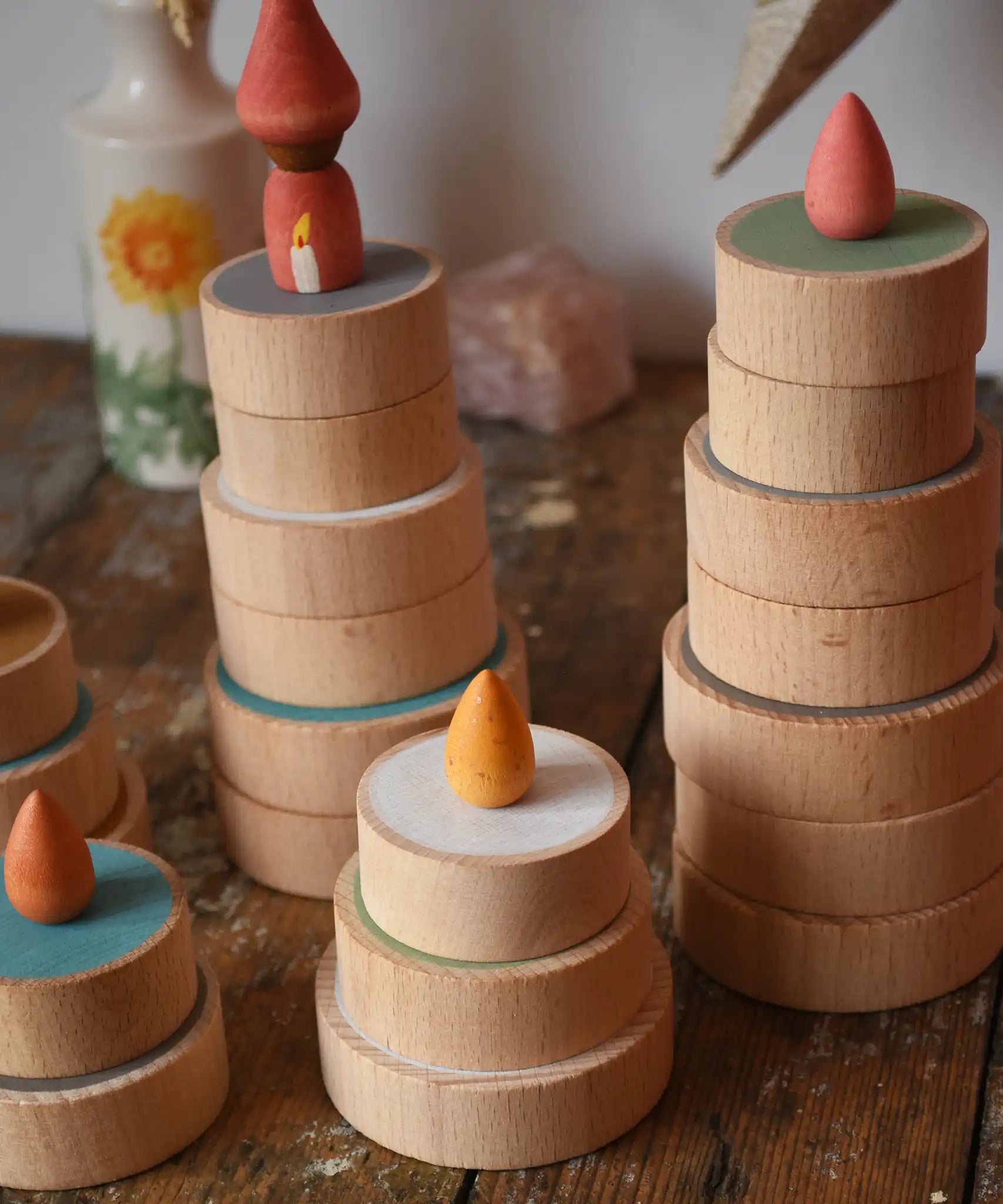 Papoose Toys wooden earth coins stacked up to create cakes with Grapat loose parts on top as candles.