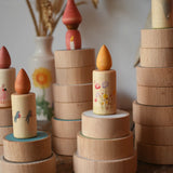 Papoose Toys wooden earth coins stacked up to create cakes with Grapat loose parts on top as candles.