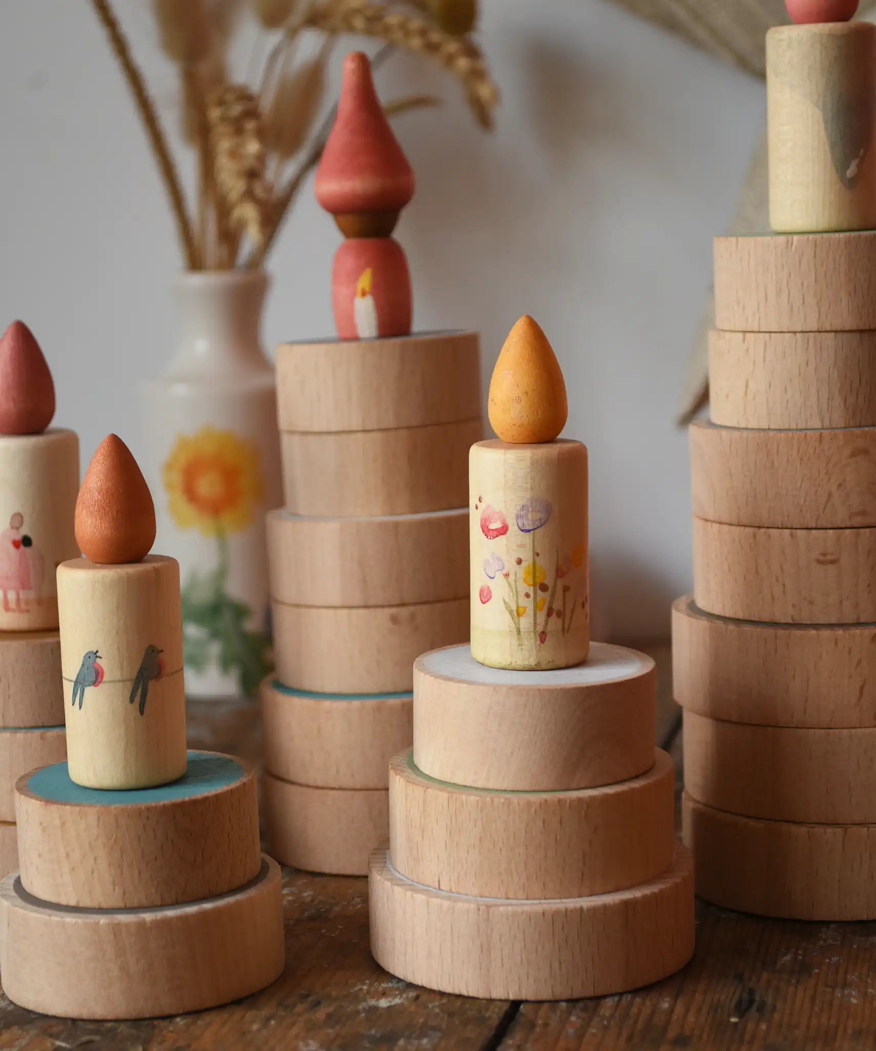 Papoose Toys wooden earth coins stacked up to create cakes with Grapat loose parts on top as candles.