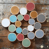 Papoose Toys wooden earth coins placed on a wooden desk in a mandala shape.
