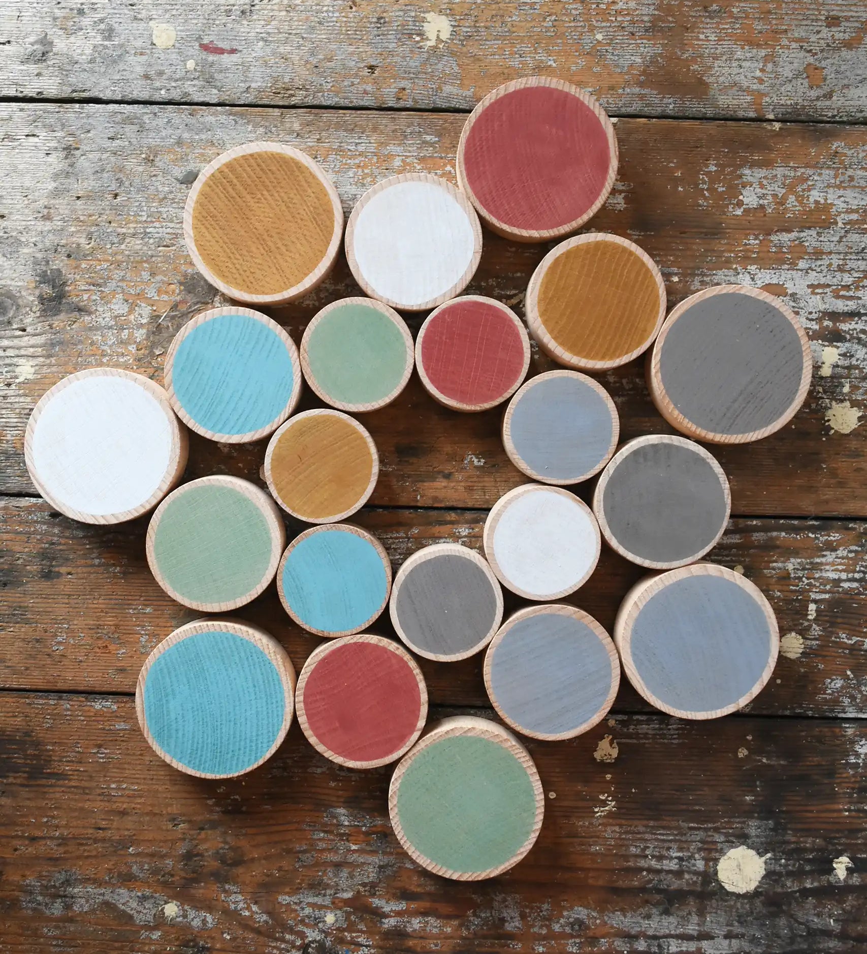 Papoose Toys wooden earth coins placed on a wooden desk in a mandala shape.
