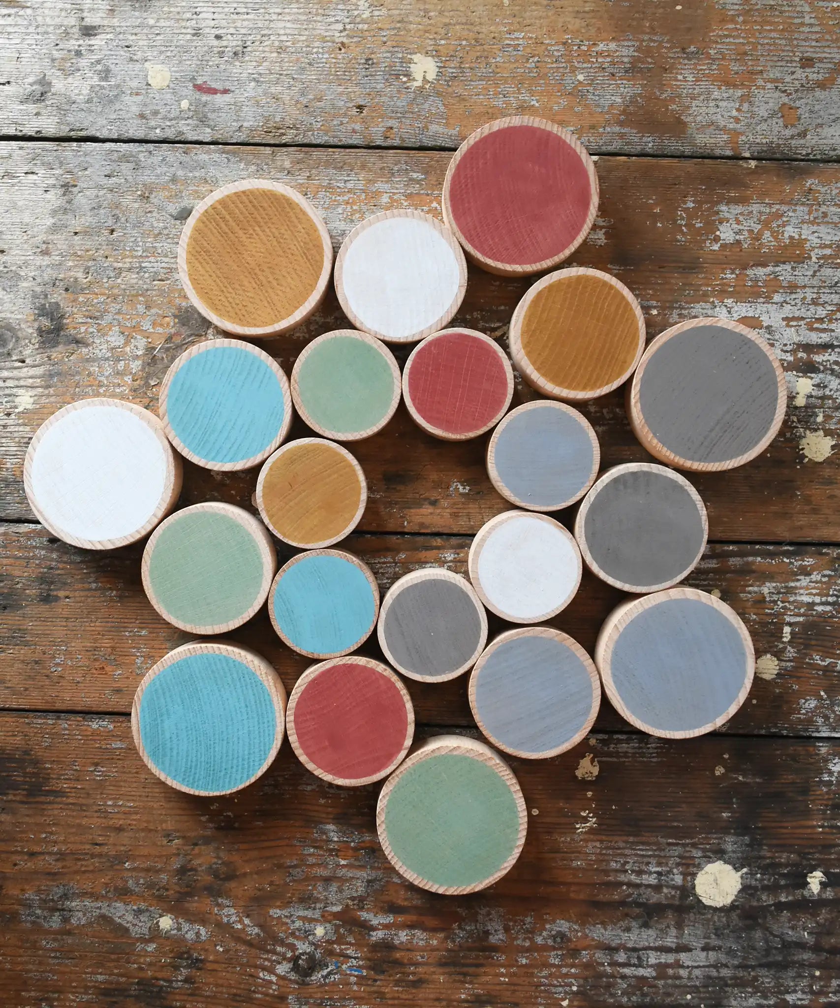 Papoose Toys wooden earth coins placed on a wooden desk in a mandala shape.