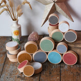Papoose Toys wooden earth coins placed on a wooden desk.