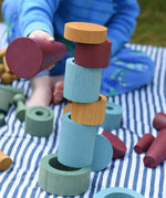 Rubes and discs from the Papoose Toys wooden earth tinker tray school set stacked up. Child knocking them down using the large red cone.