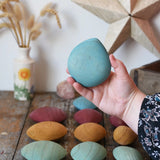 Large blue pebble from the Papoose Toys earth wooden pebbles set in an adult's hand.