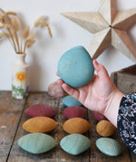 Large blue pebble from the Papoose Toys earth wooden pebbles set in an adult's hand.