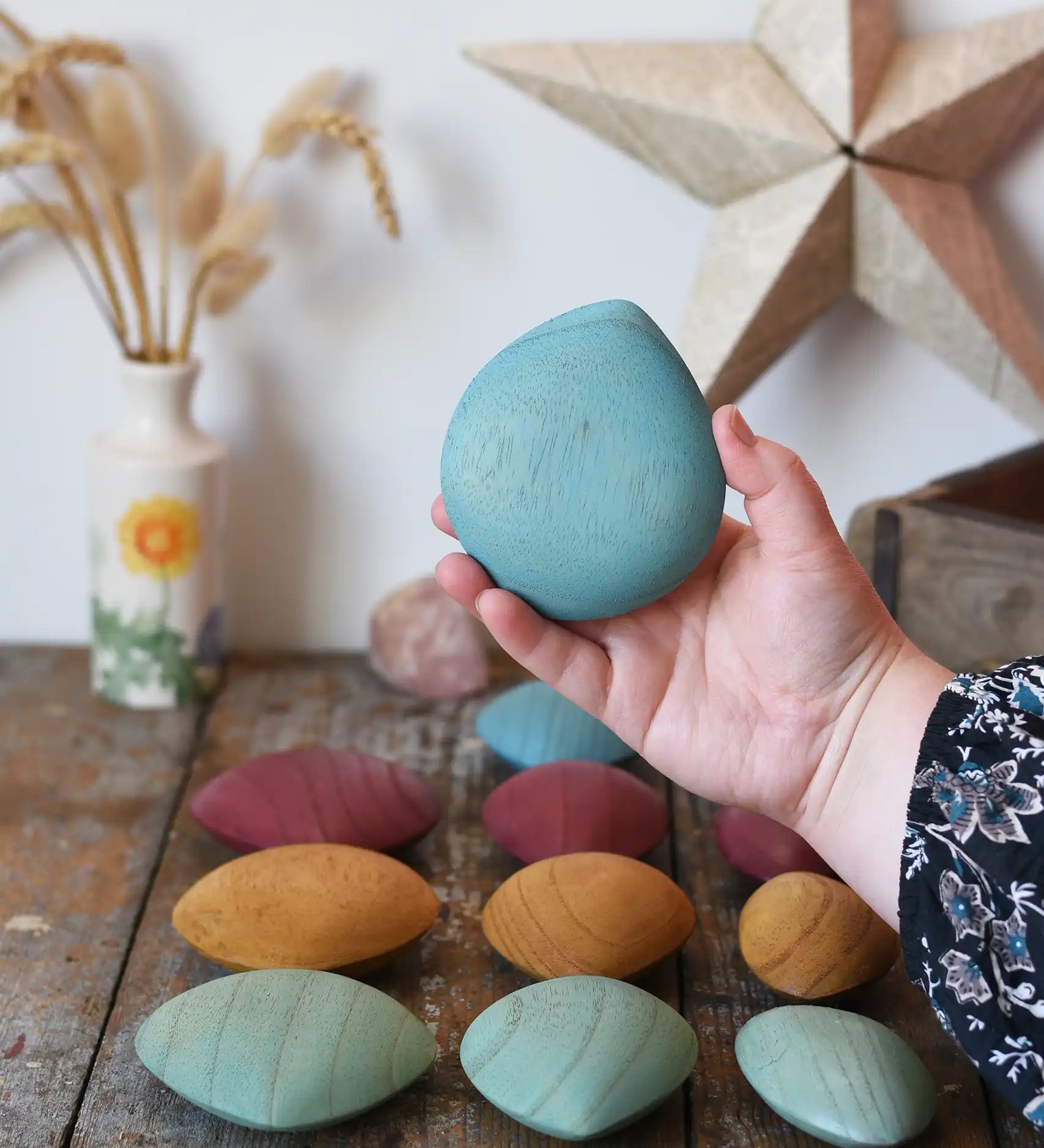 Large blue pebble from the Papoose Toys earth wooden pebbles set in an adult's hand.