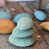 Three green peblles from the Papoose Toys earth wooden pebbles  stacked up on top of each other.