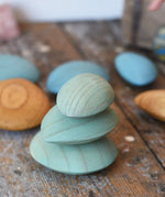 Three green peblles from the Papoose Toys earth wooden pebbles  stacked up on top of each other.