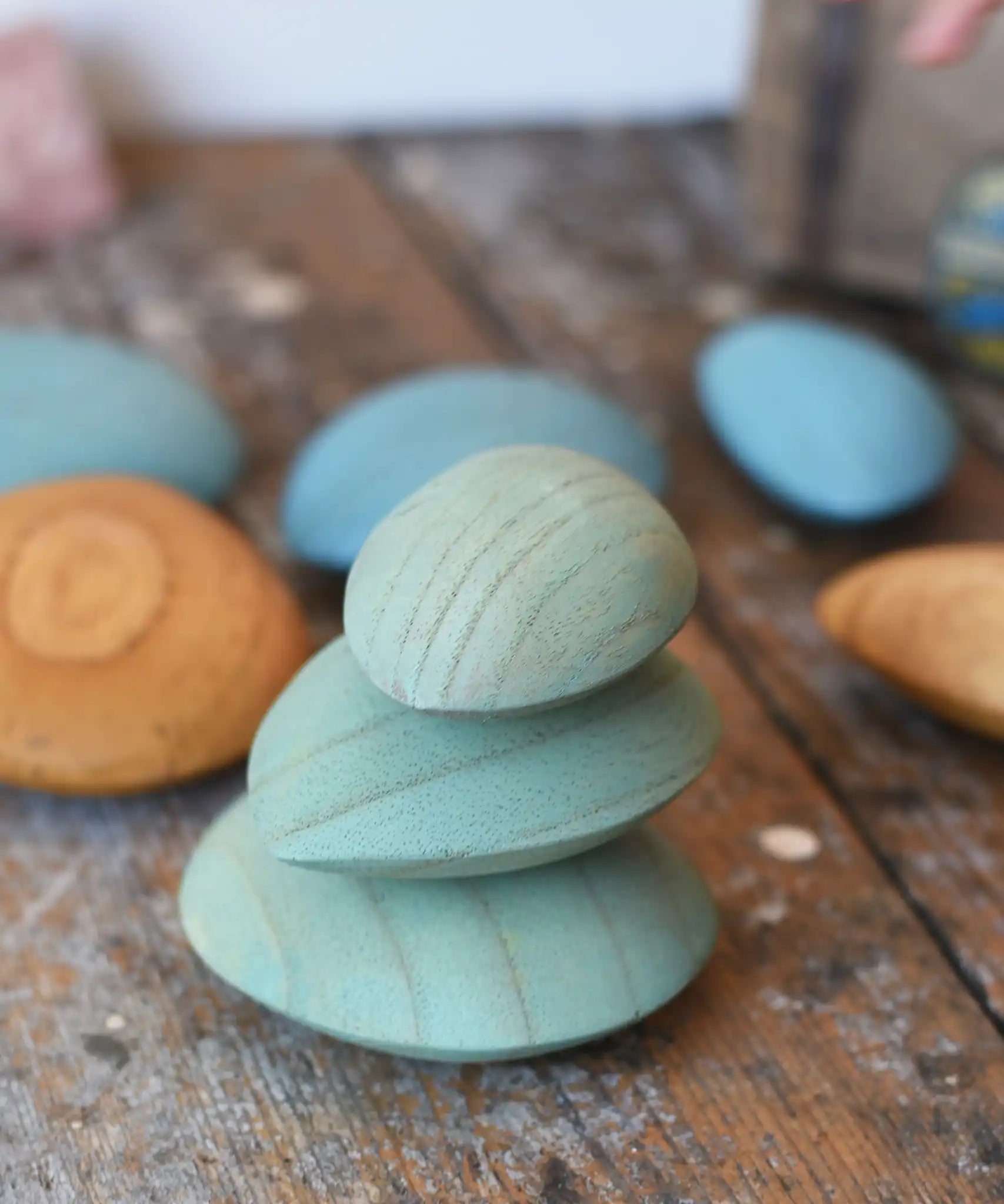 Three green peblles from the Papoose Toys earth wooden pebbles  stacked up on top of each other.