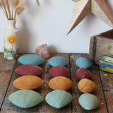 Papoose Toys earth wooden pebbles placed on a wooden desk.