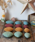 Papoose Toys earth wooden pebbles placed on a wooden desk.