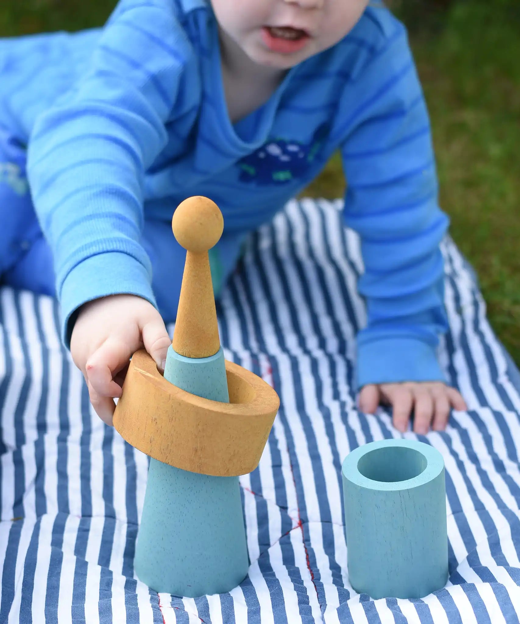 Child playing with pieces from the Papoose Toys wooden earth tinker tray school set.