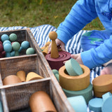 Child playing with the Papoose Toys wooden earth tinker tray school set outdoors.