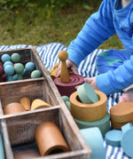 Child playing with the Papoose Toys wooden earth tinker tray school set outdoors.