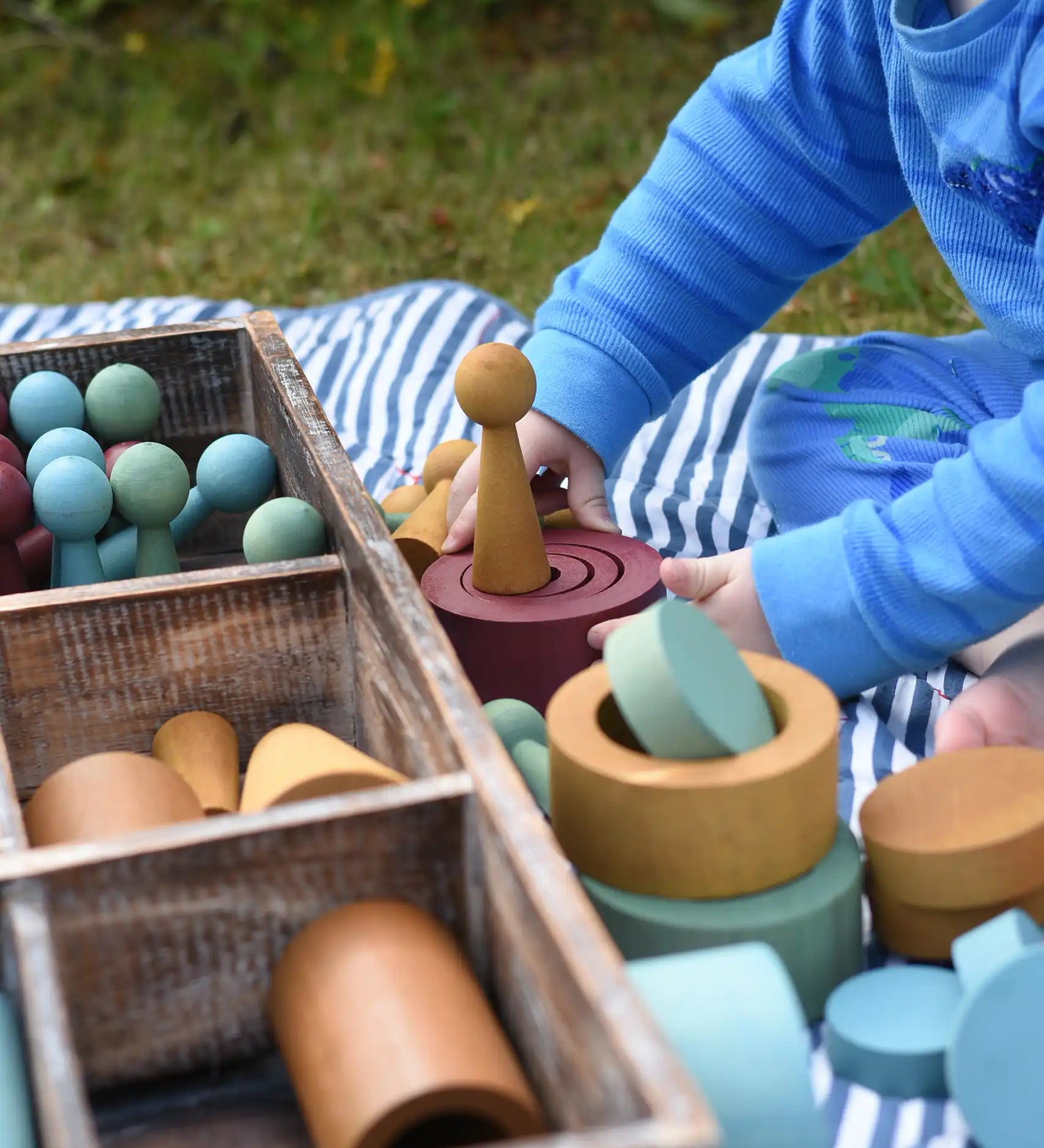 Child playing with the Papoose Toys wooden earth tinker tray school set outdoors.