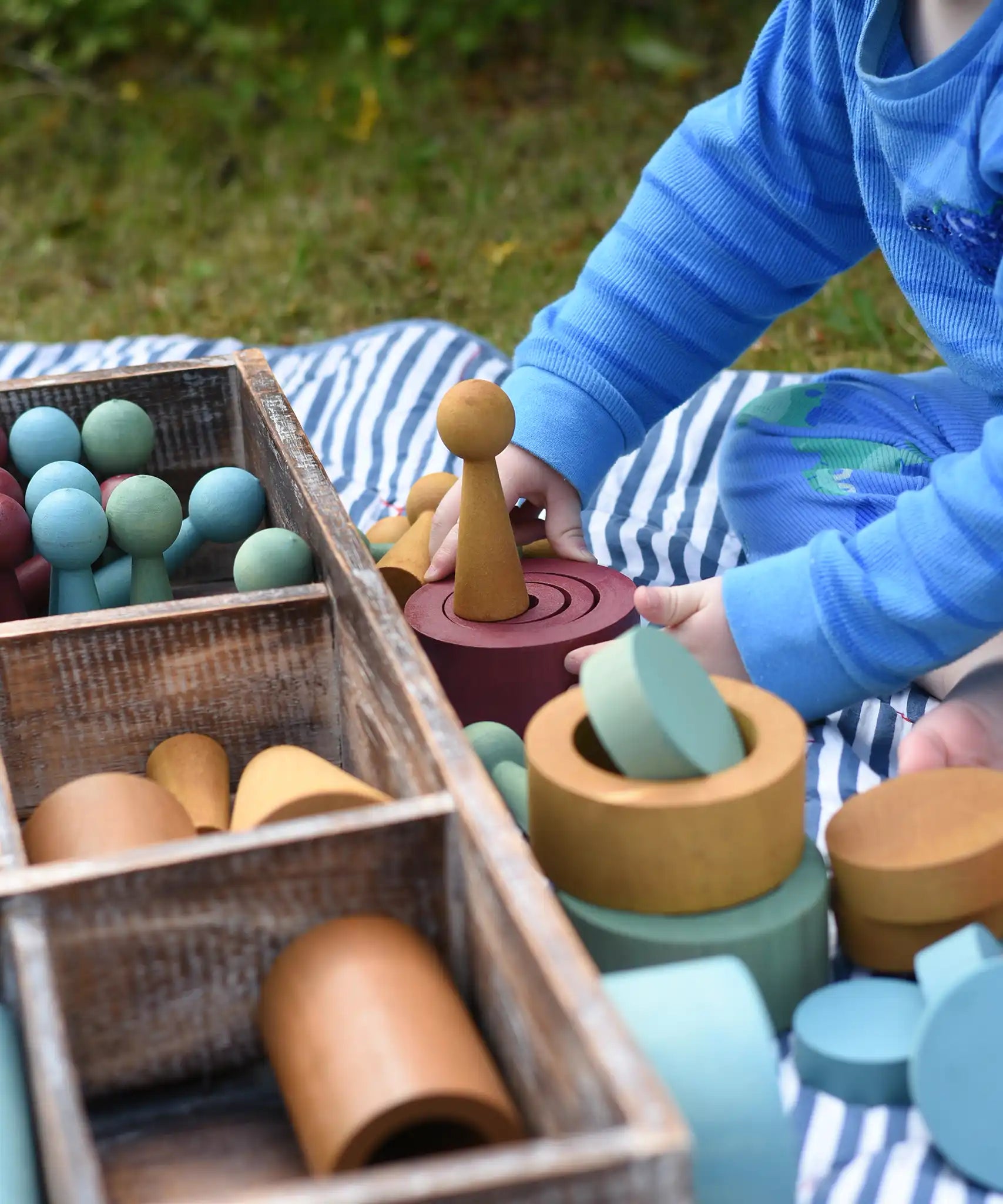 Child playing with the Papoose Toys wooden earth tinker tray school set outdoors.