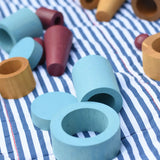 Blue peces from the Papoose Toys wooden earth tinker tray school set placed on a striped blanket.