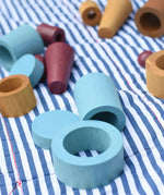 Blue peces from the Papoose Toys wooden earth tinker tray school set placed on a striped blanket.