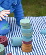 Stacking discs from the Papoose Toys wooden earth tinker tray school set stacked up on a striped blanket. 