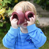 Child holding two pieces from the red earth Papoose Nesting tubes up to his eyes.