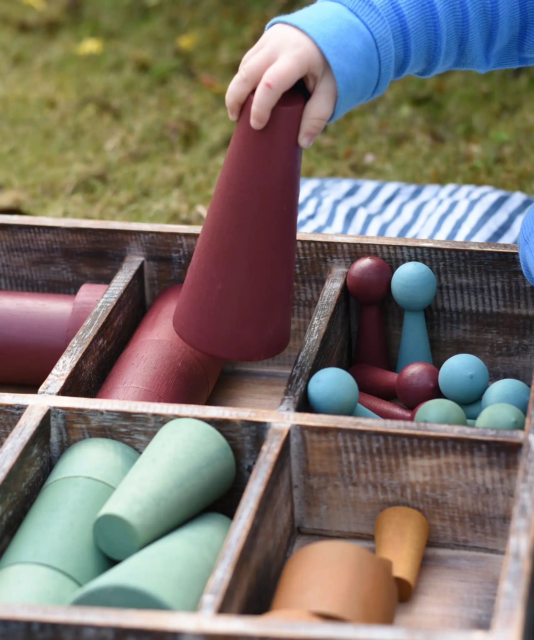 Close up of the Papoose Toys wooden earth tinker tray school set with the large red cone in a child's hand.