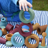Child stacking and balancing earth coloured wooden tubes on top of each other.