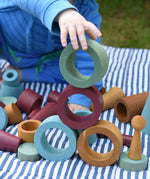 Child stacking and balancing earth coloured wooden tubes on top of each other.