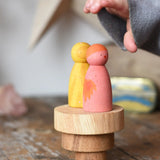 Papoose Toys wooden natural stacking discs on a wooden desk with Grapat Wild Crew peg dolls placed on top. 