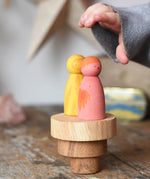 Papoose Toys wooden natural stacking discs on a wooden desk with Grapat Wild Crew peg dolls placed on top. 