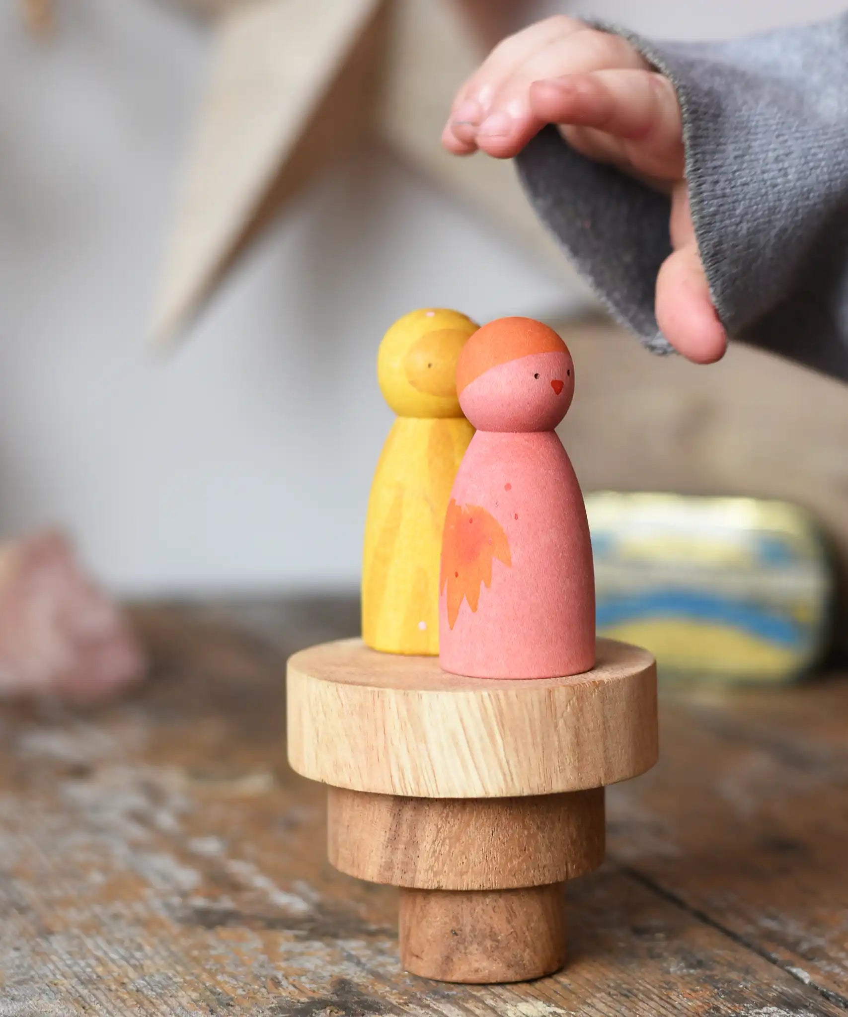 Papoose Toys wooden natural stacking discs on a wooden desk with Grapat Wild Crew peg dolls placed on top. 