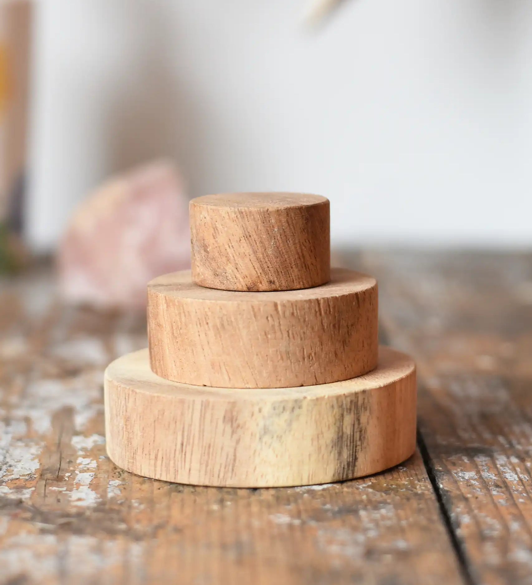 Papoose Toys wooden natural stacking discs on a wooden desk. 