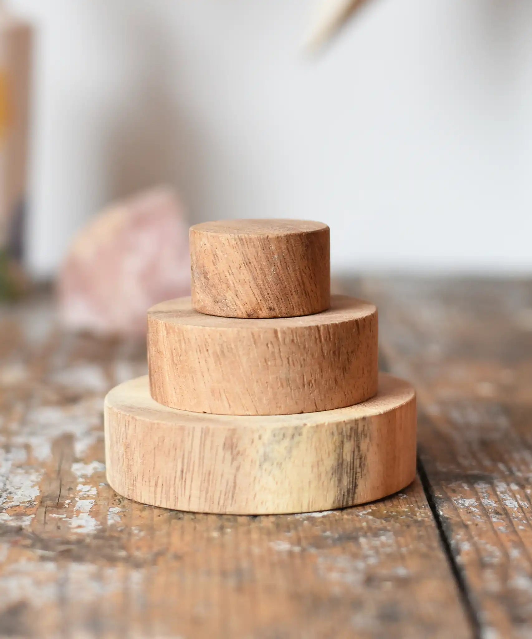 Papoose Toys wooden natural stacking discs on a wooden desk. 