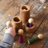 Papoose Toys wooden stacking tubes placed on a wooden surface with Goathe rainbow people placed on and inside the tubes.