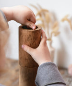 Child playing with Papoose Toys wooden stacking tubes placing something inside one tube.