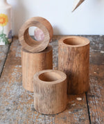 Papoose Toys wooden stacking tubes placed on a wooden surface.