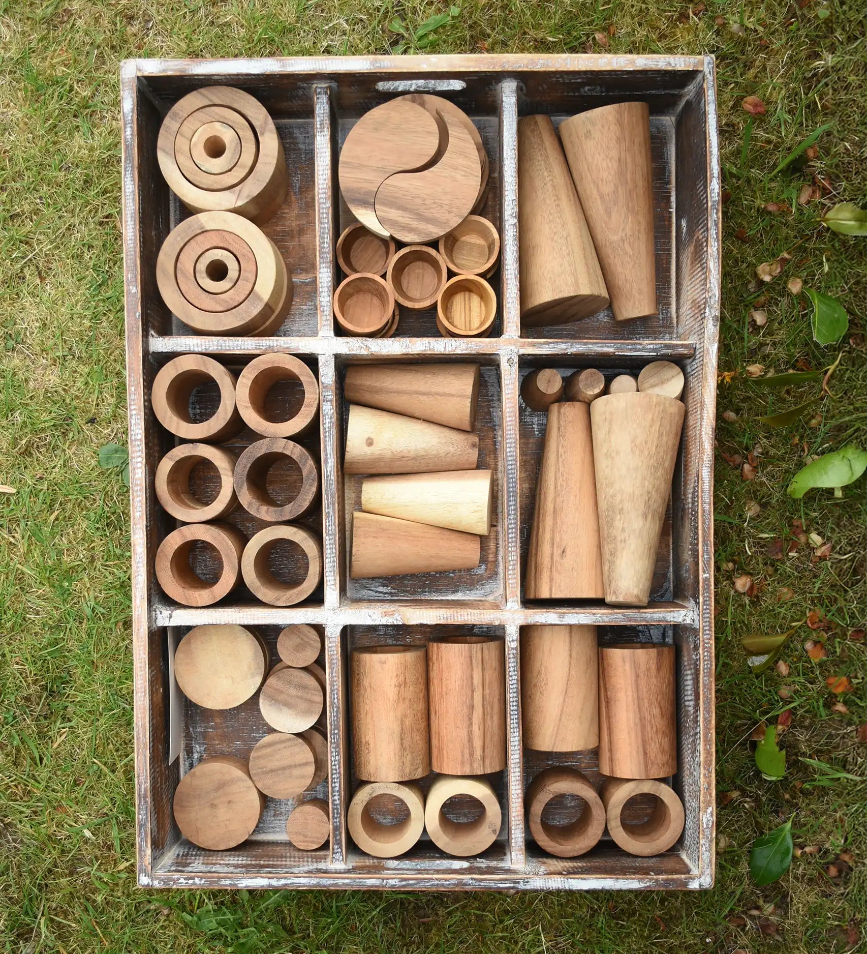 Papoose Toys wooden tinker tray school set placed on grass.